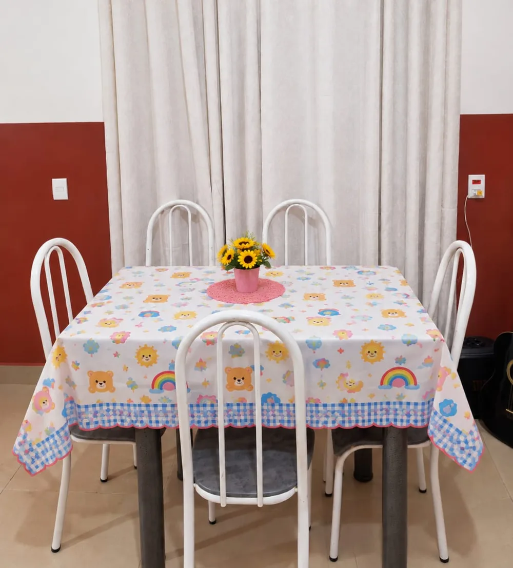 Mesa das refeições com toalha de ursinhos e vaso de girassóis